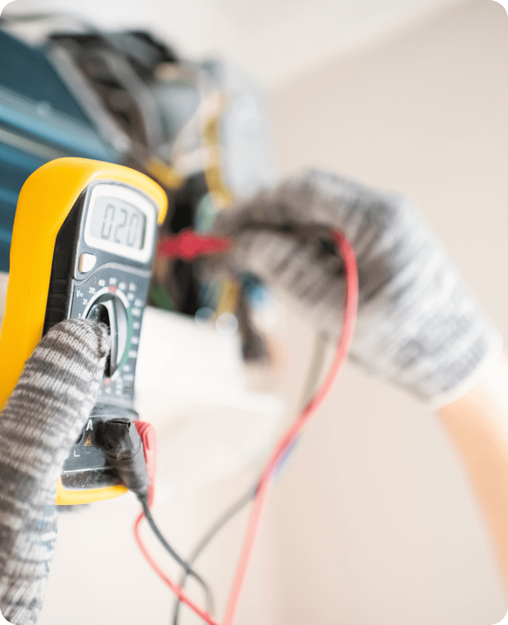 Person measuring voltage with a digital multimeter, wearing gloves.