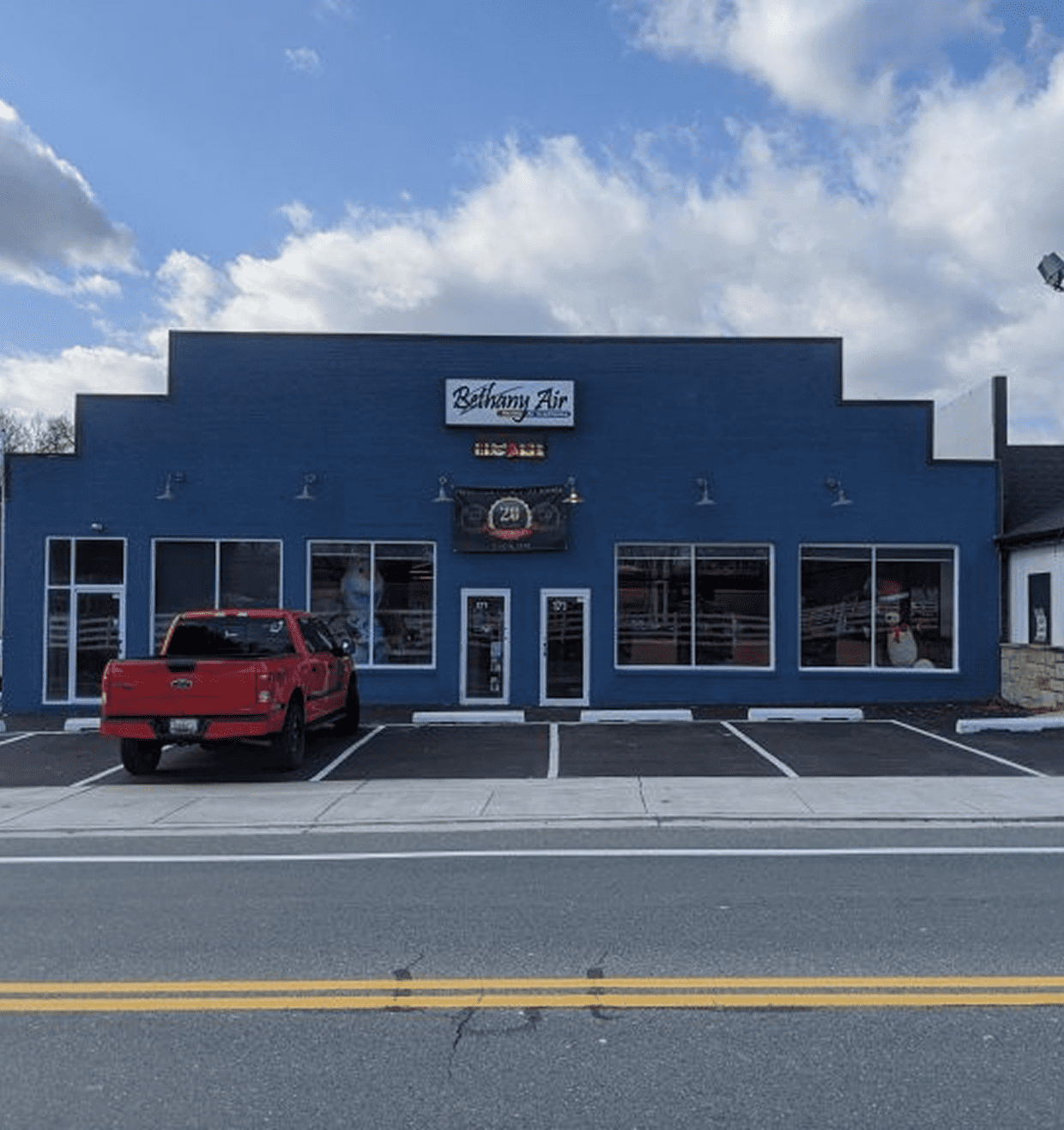 A blue building with a sign reading "The Shop" and a red truck parked outside.