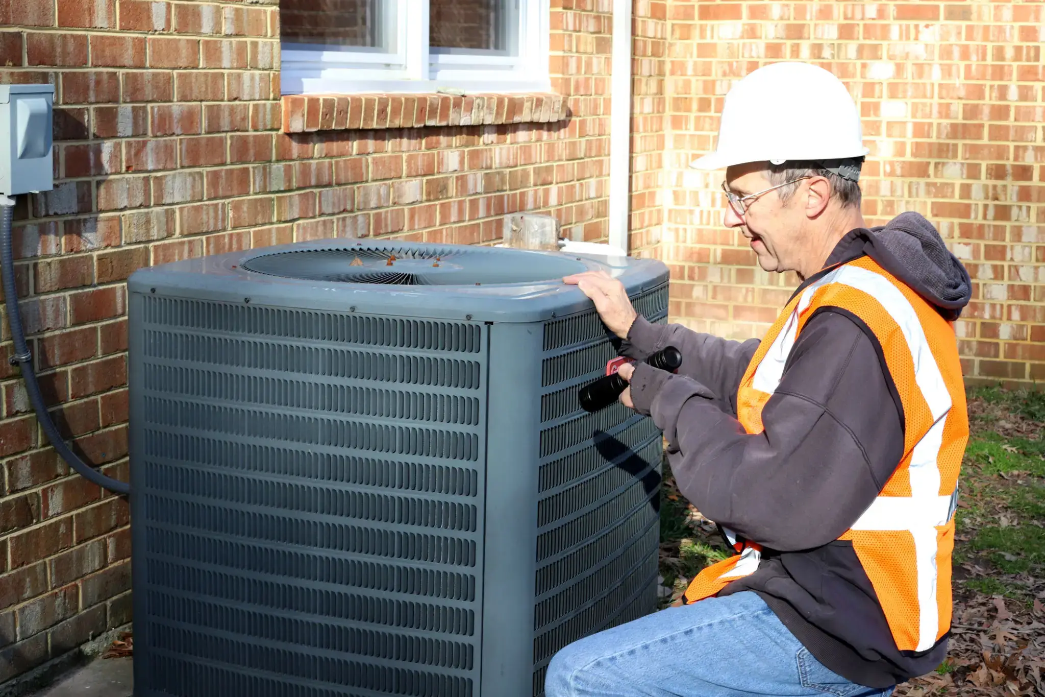 Technician inspecting an HVAC unit outdoors.