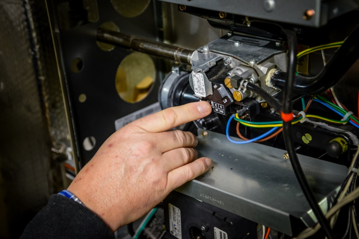 HVAC Contractor in Downtown Annapolis, MD HVAC technician from the HVAC contractor in Downtown Annapolis, MD, adjusting the gas valve on a heating system.