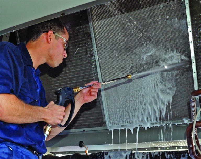 Technician cleaning HVAC coils during professional AC maintenance service in Edgewater MD.