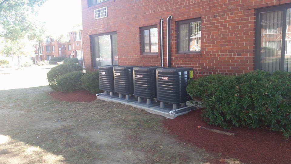 Residential AC condenser units installed outside apartment building for professional AC repair in Edgewater MD.
