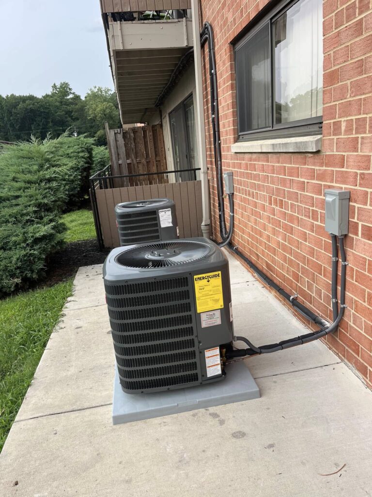Outdoor AC condenser units installed beside a residential building for HVAC repair and cooling services in Edgewater MD.