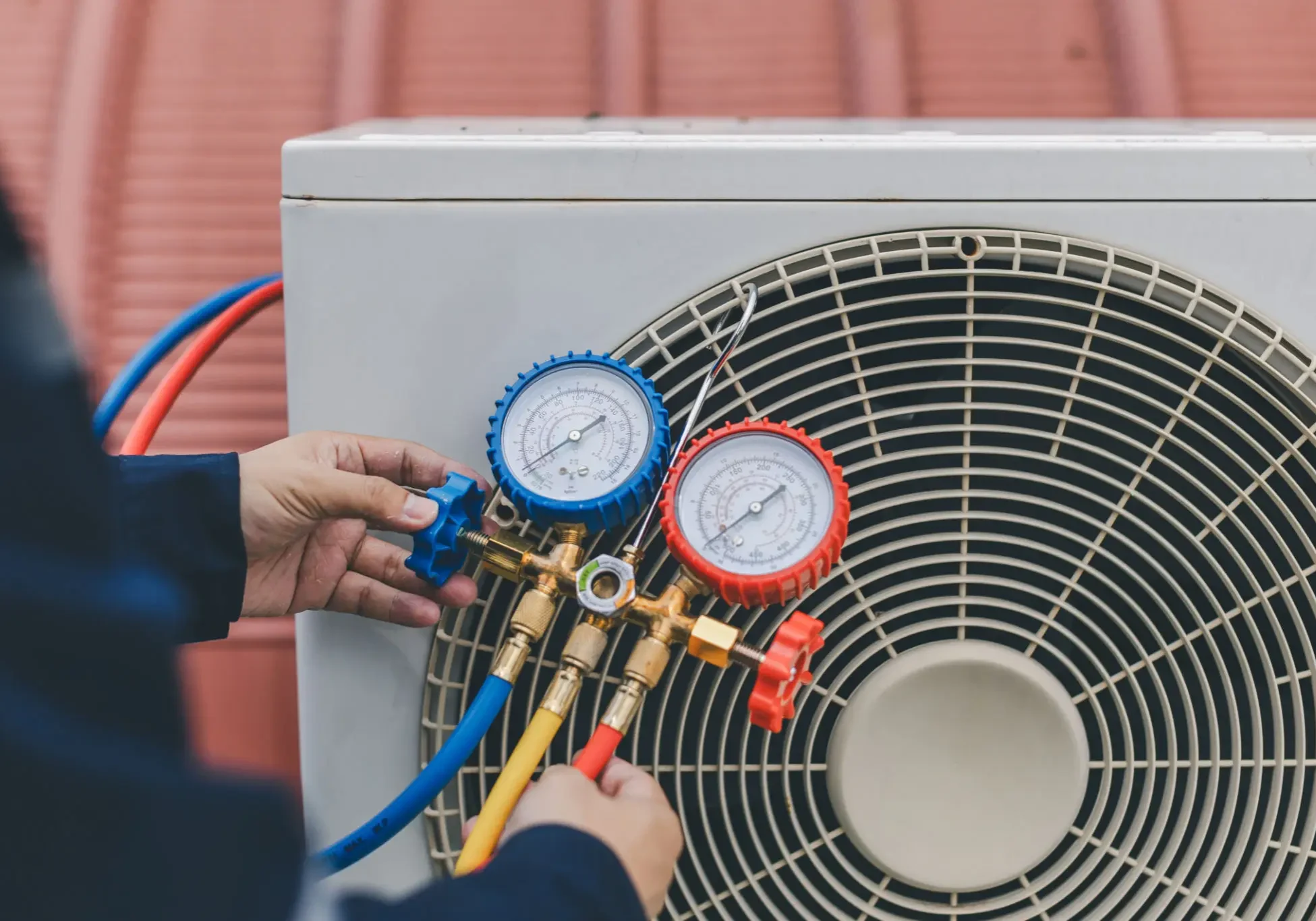 Technician adjusting HVAC gauges on an outdoor air conditioning unit.