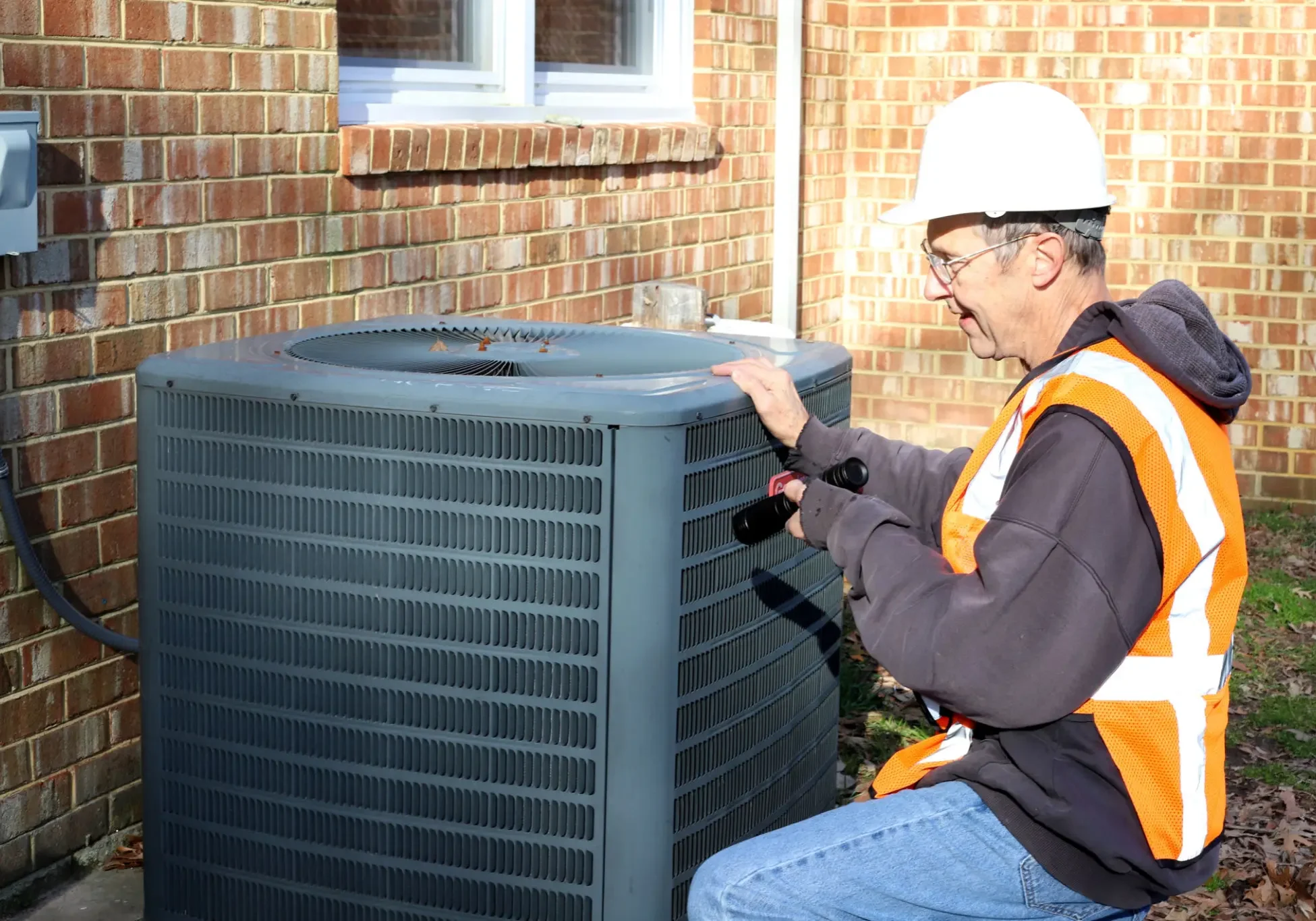 Technician inspecting an HVAC unit outdoors.